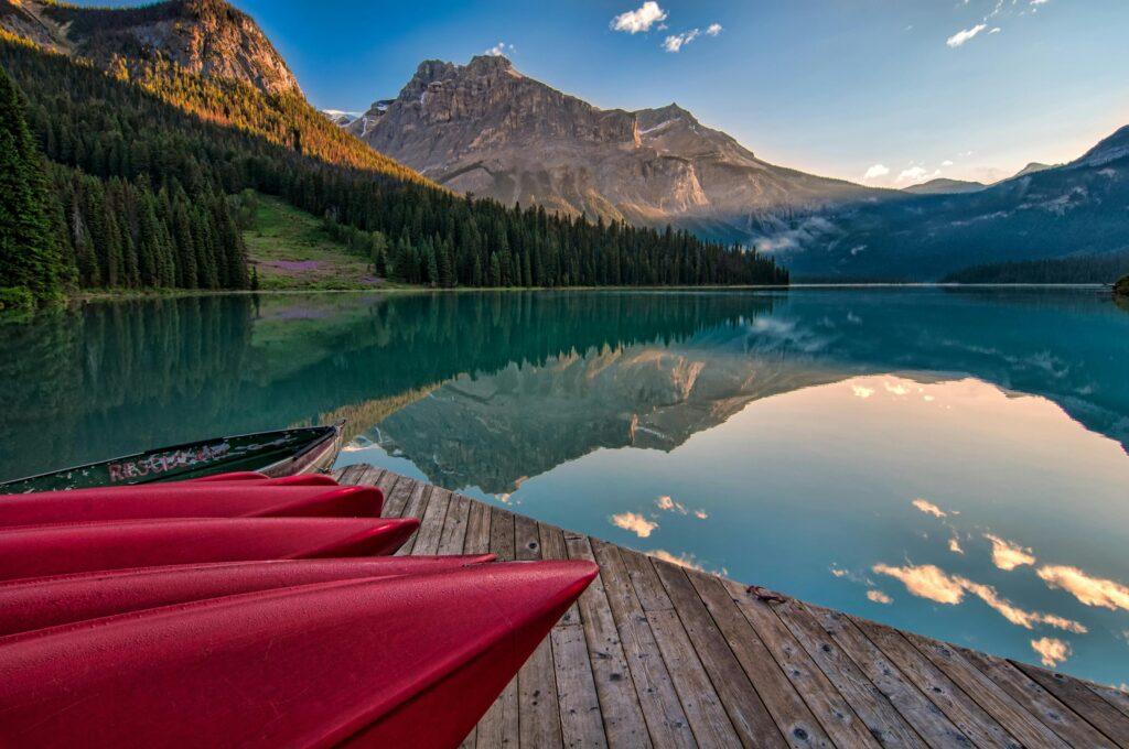 Vibrant red canoes on Emerald Lake with stunning mountain reflections at sunrise in British Columbia.