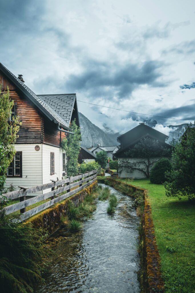 Picturesque village scene in Hallstatt, Austria with traditional houses and a serene stream.